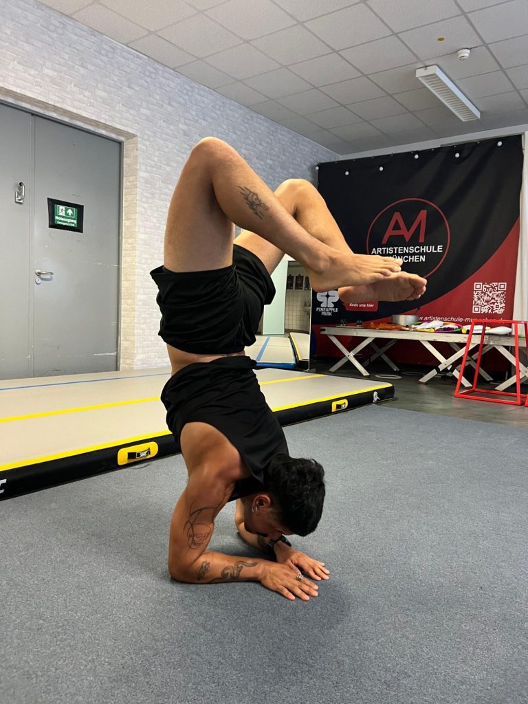 Mann macht einen Handstand auf dem Kopf in einem Fitnessraum.